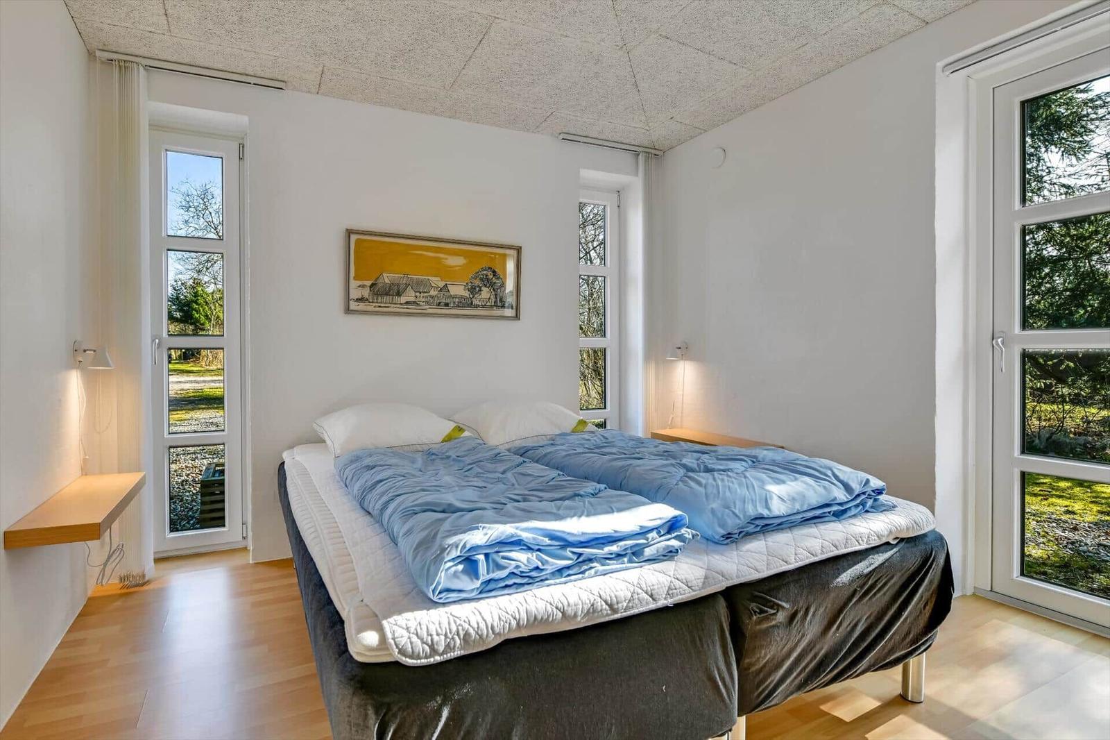 Schlafzimmer mit Doppelbett, Fenstern und Holzboden.