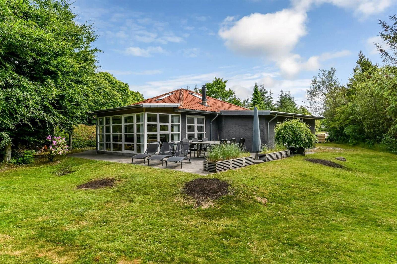Moderne Villa mit Terrasse, Garten und Blick auf Bäume.