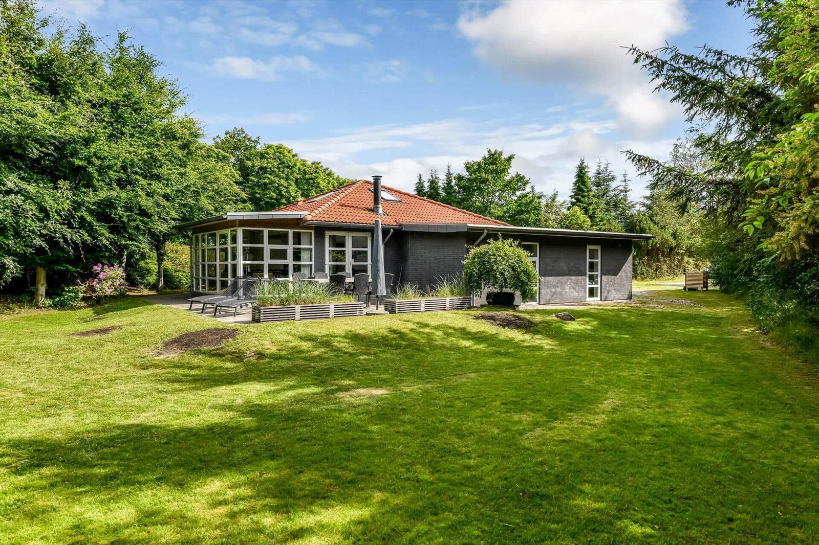 Moderne Villa mit Terrasse und Garten. Umgeben von Bäumen und Grünflächen.