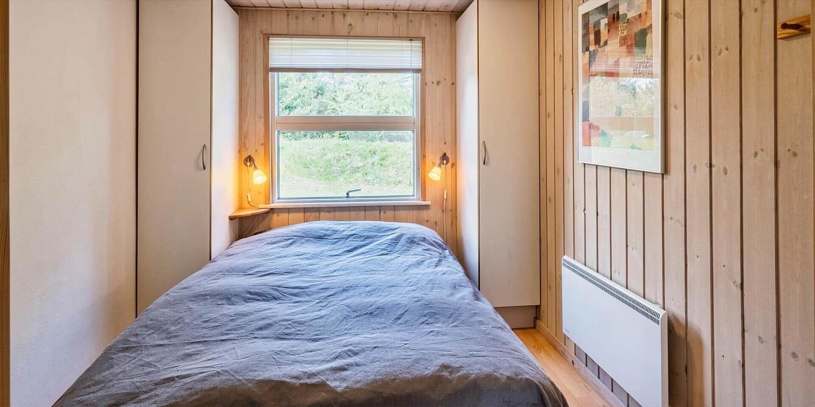 Schlafzimmer mit Bett, Fenster und Holzwand