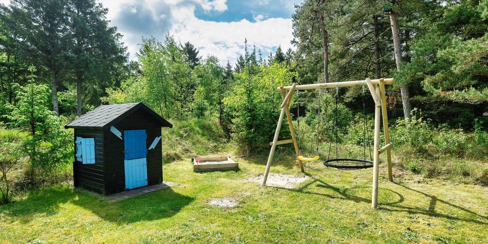 Hinterhof mit Spielplatz, Sandkasten und kleinem Holzhaus mit blauer Tür.