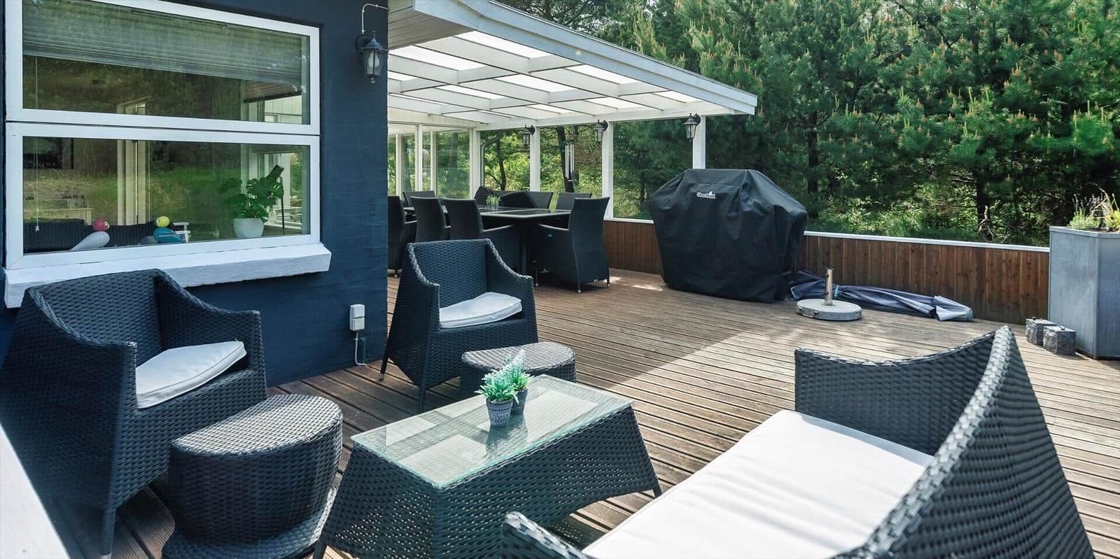 Terrasse mit Sitzgruppe, Grill und Blick in den Wald.