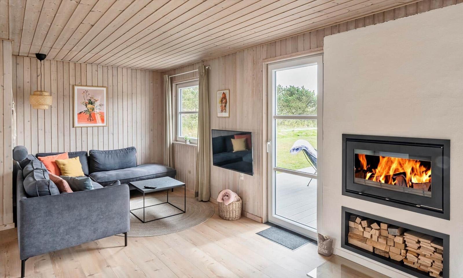 Wohnzimmer mit Sofa, Kamin und Blick auf die Terrasse.