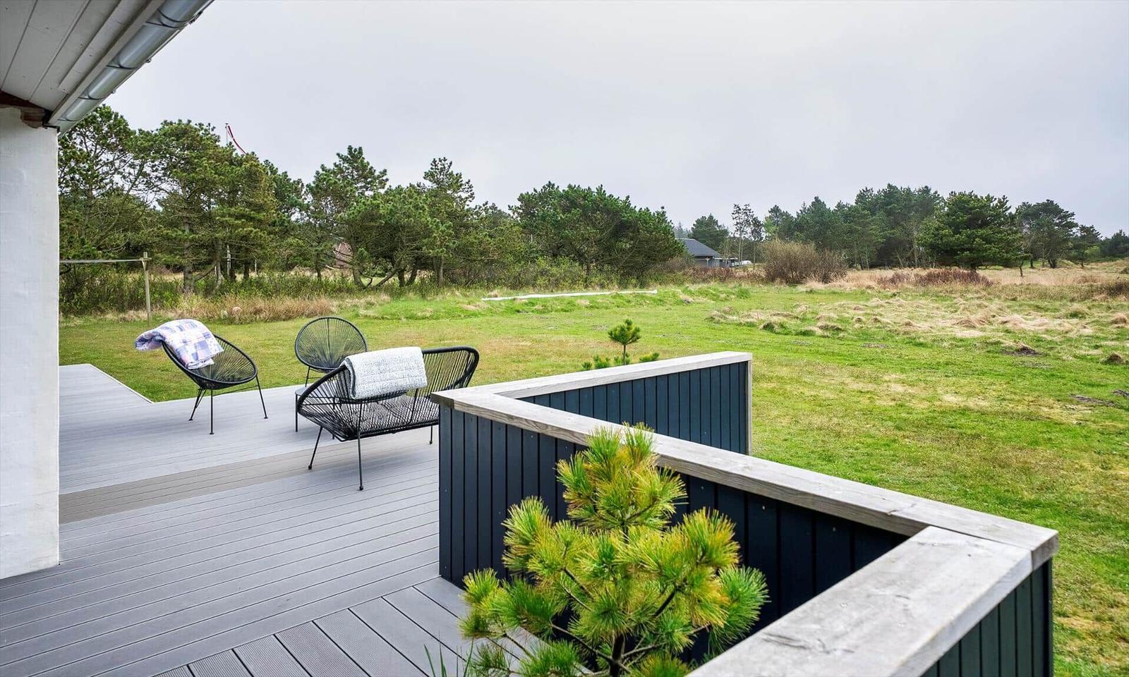 Terrasse mit zwei Stühlen und Blick auf grünes Feld und Bäume.
