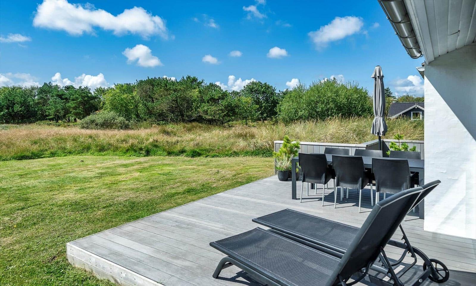 Terrasse mit Liegestühlen und Tisch unter blauem Himmel