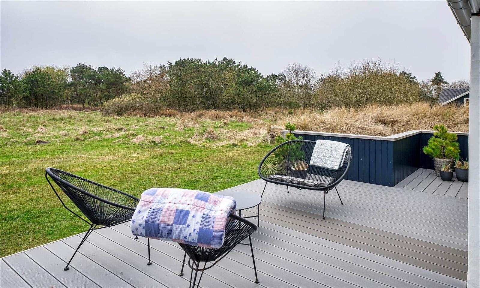 Terrasse mit zwei Stühlen und Tisch. Blick auf Grasland und Bäume.