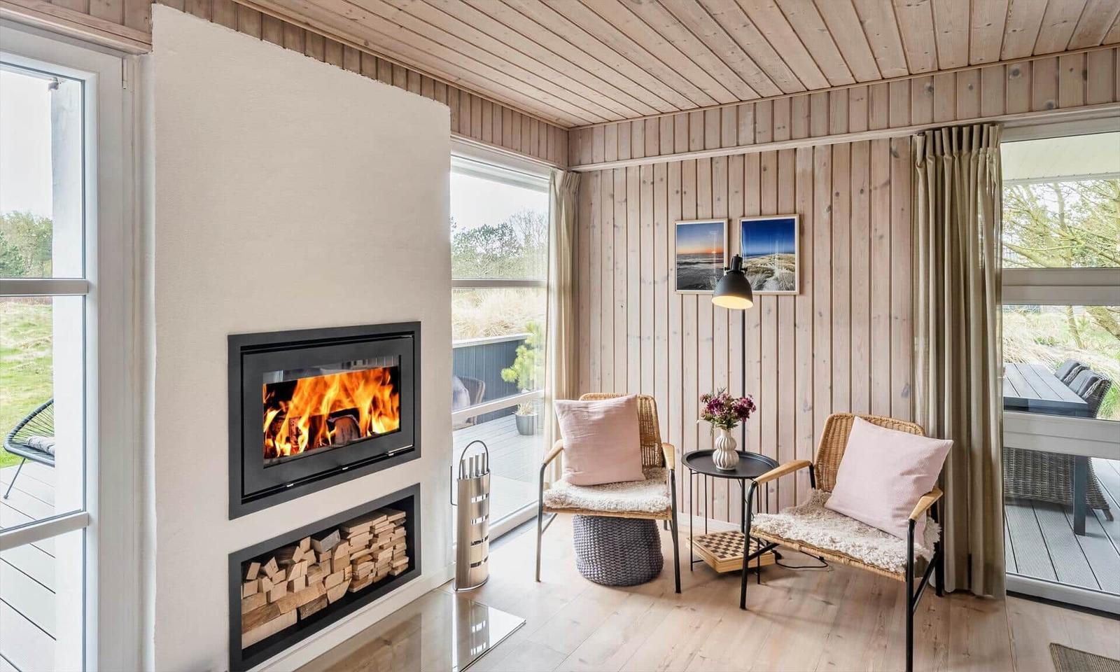 Raum mit Kamin, zwei Stühlen und Blick auf Balkon.