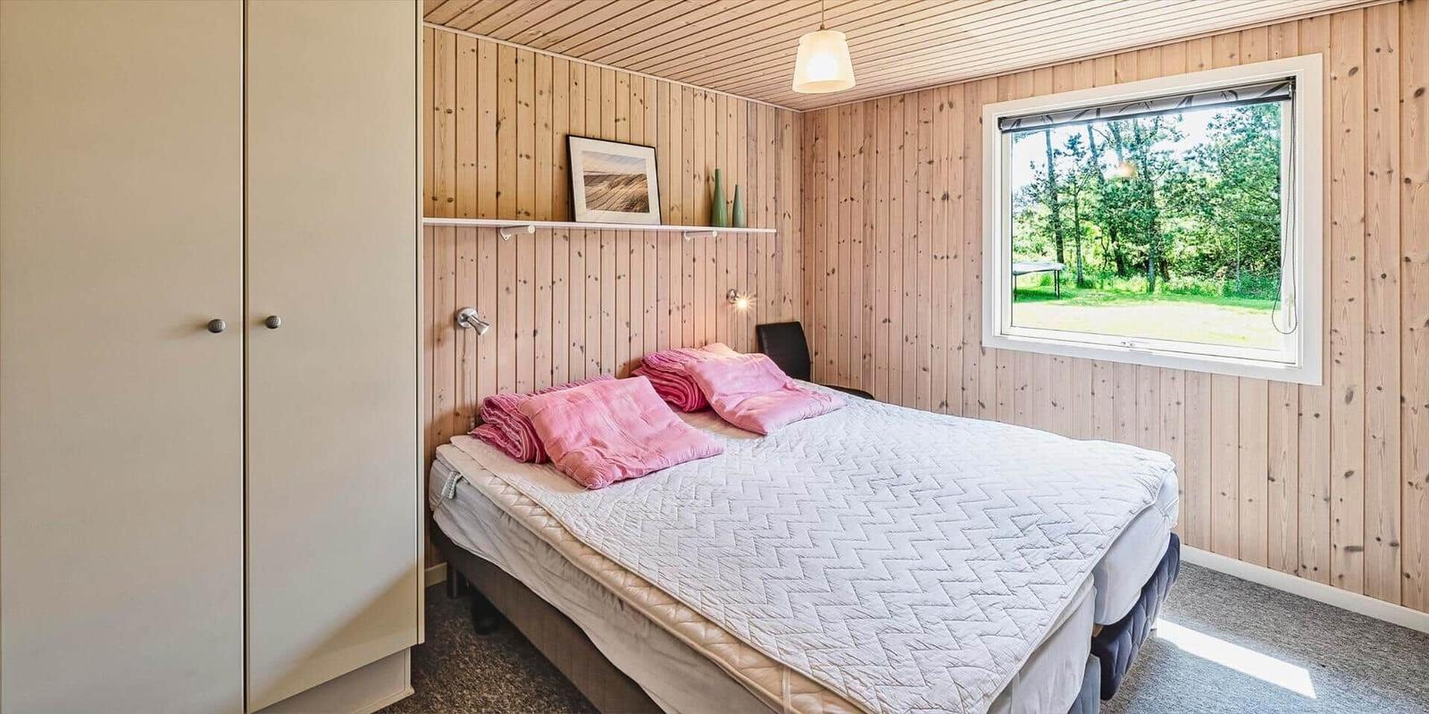 Schlafzimmer mit Bett, Kleiderschrank und Fenster zum Garten