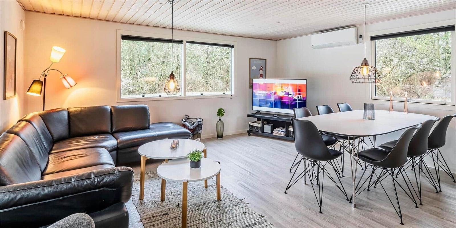 Wohn- und Essbereich mit Ledersofa, Esstisch und TV.