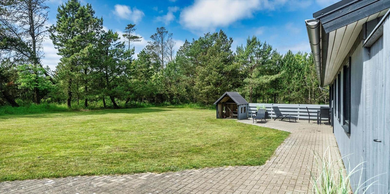Hinterhof mit Garten, Terrasse und kleinem Holzhaus.