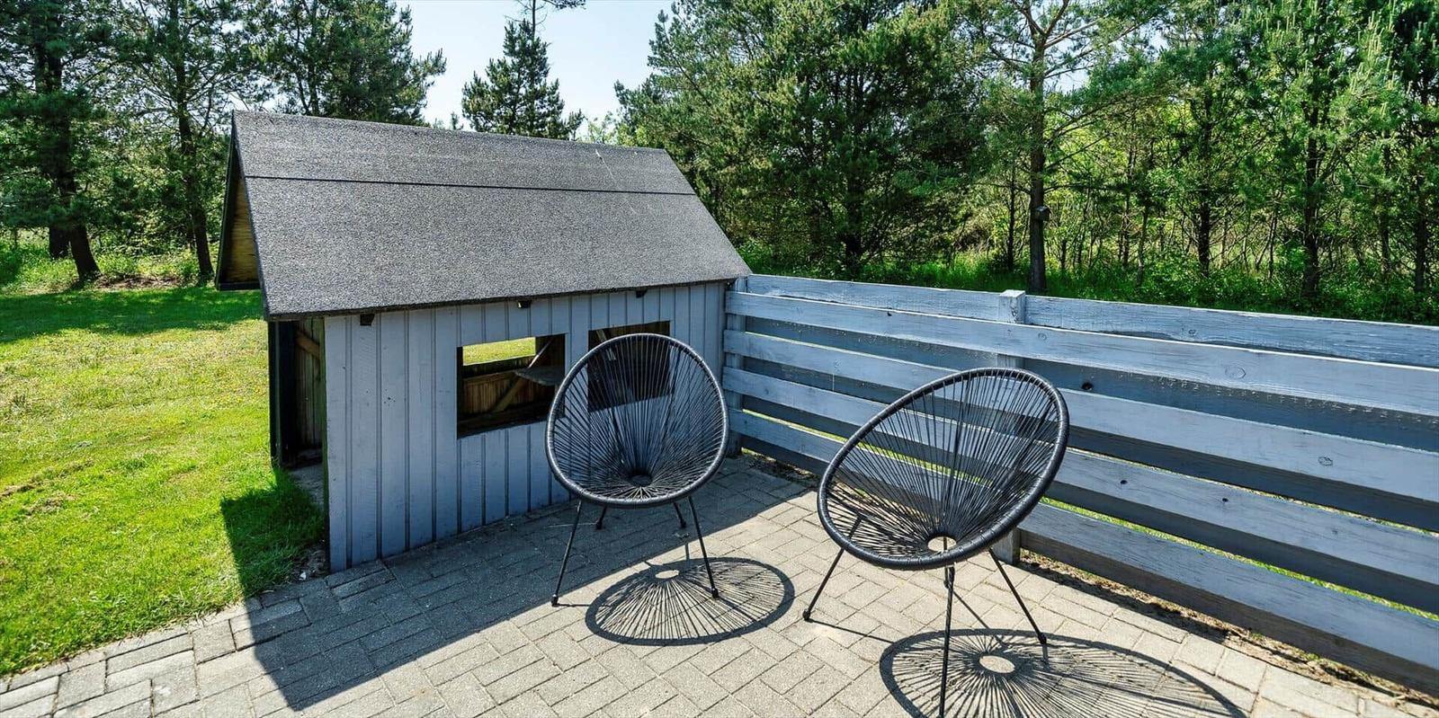 Terrasse mit zwei Stühlen neben einem kleinen Haus im Wald.