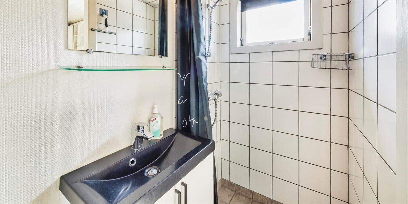 Badezimmer mit Dusche, Waschbecken und Spiegel