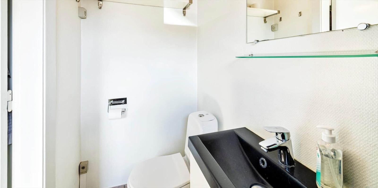 Badezimmer mit Toilette, Waschbecken und Spiegel