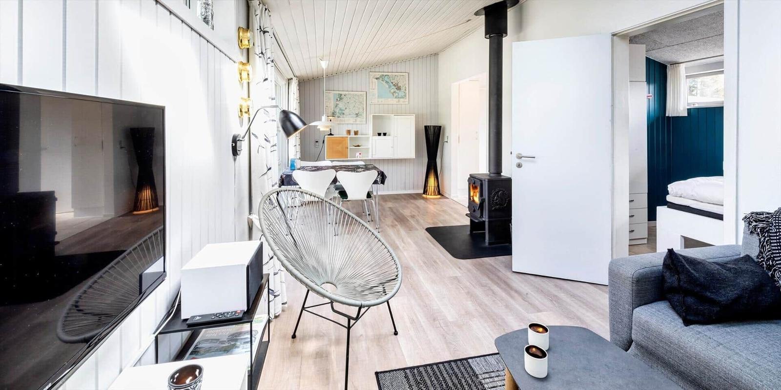 Wohnbereich mit Fernseher, Sessel und Kaminofen. Durchgang zur Schlafstube mit blauer Wand.