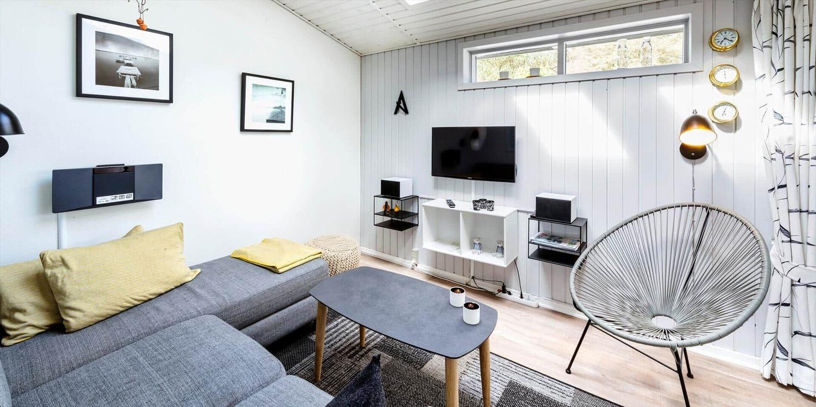 Wohnzimmer mit Sofa, Fernseher und Stuhl. Wand mit Bildern und Uhren.