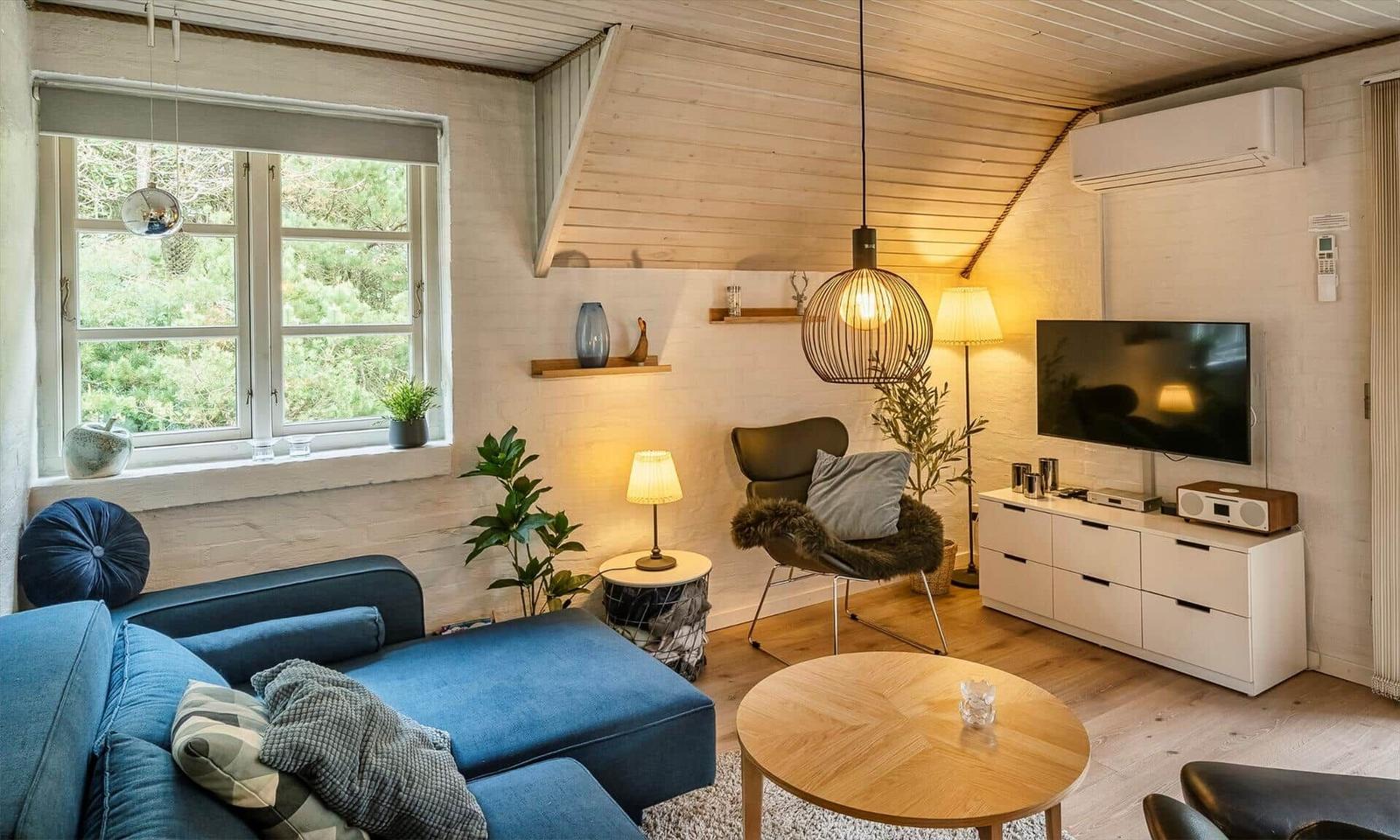 Ein Wohnzimmer mit blauem Sofa, Holztisch und Fernseher an der Wand.