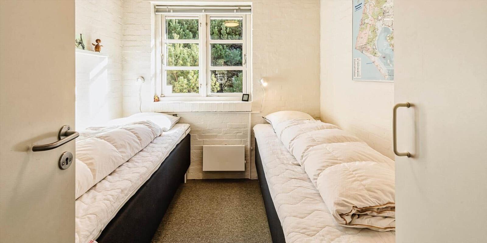 Zwei Betten in einem Raum mit Fenster und Karte an der Wand.