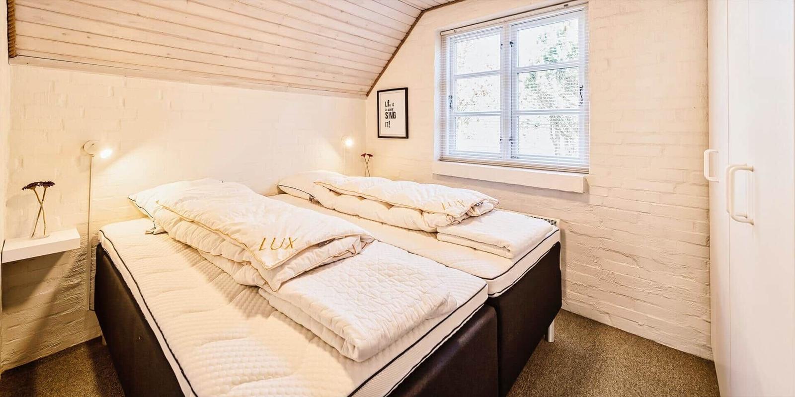 Schlafzimmer mit zwei Matratzen, weißer Wand und Fenster.
