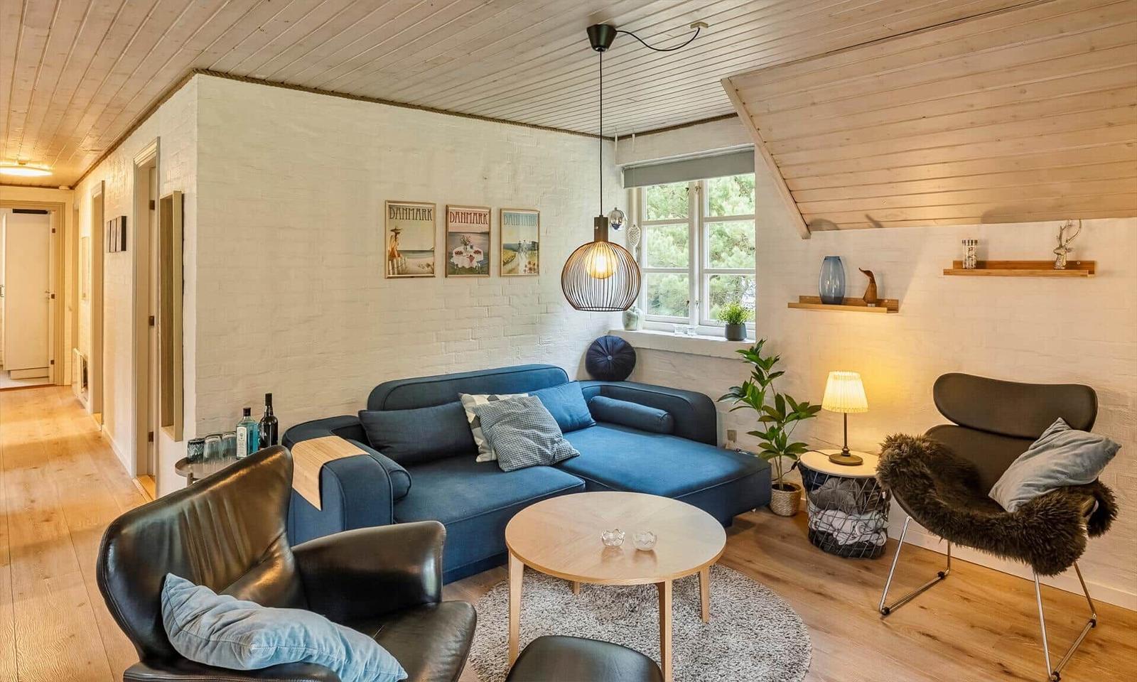 Ein Wohnzimmer mit blauem Sofa, zwei Sesseln und einem runden Tisch.