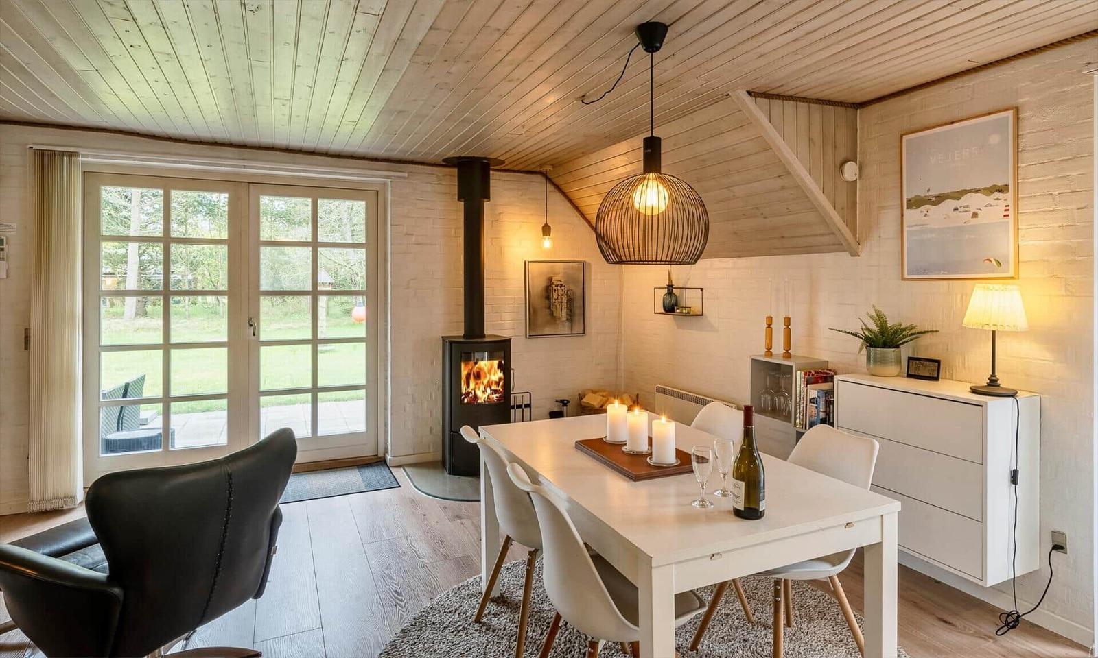 Esszimmer mit Tisch, Stühlen und Kamin. Durchgangstür zum Garten.