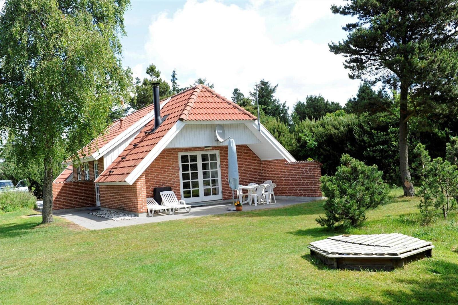 Haus mit Terrasse, Garten und Grillplatz. Weiße Möbel und roter Dachziegel.