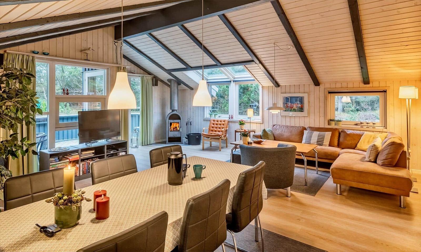 Wohn- und Essbereich mit Holzdecke, Kamin und großem Fenster