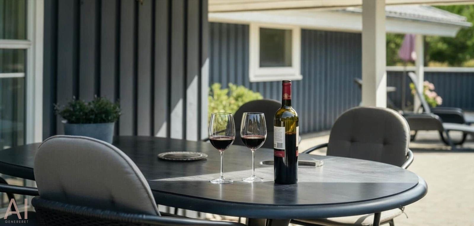 Runder Tisch mit zwei Gläsern und einer Flasche Wein auf der Terrasse.