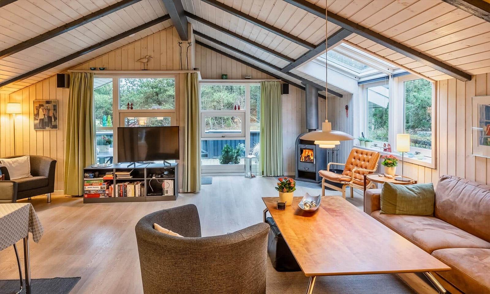 Wohnzimmer mit Holzboden, Kamin und großem Fensterbereich.