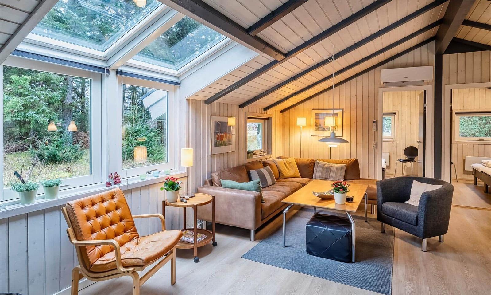 Wohnzimmer mit Sofa, Sitzgelegenheiten und Fenstern zum Garten.