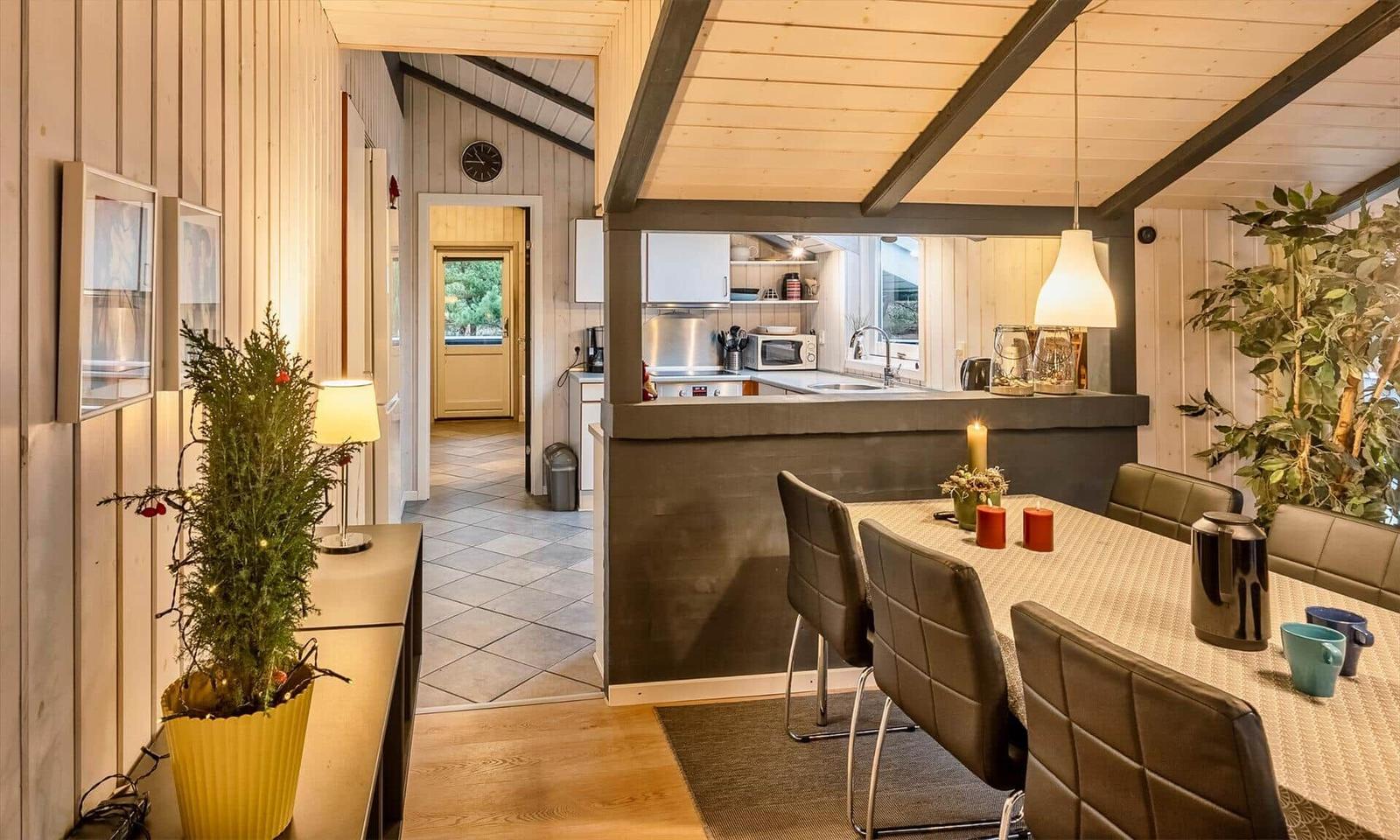 Essbereich mit Tisch und Stühlen, Küche im Hintergrund, Holzwände und Decke