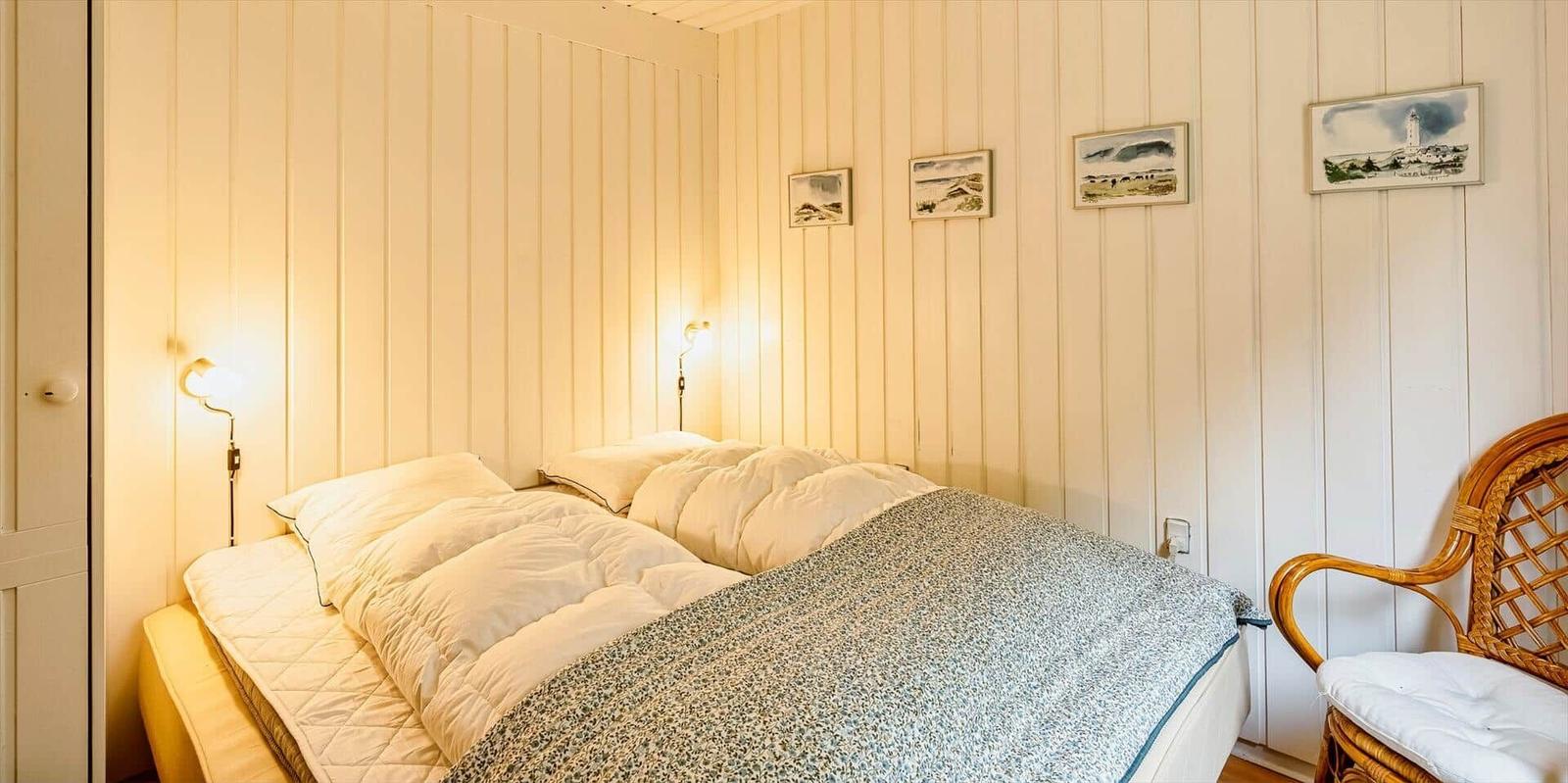 Schlafzimmer mit Bett, Wandleuchten und Stuhl an der Wand.
