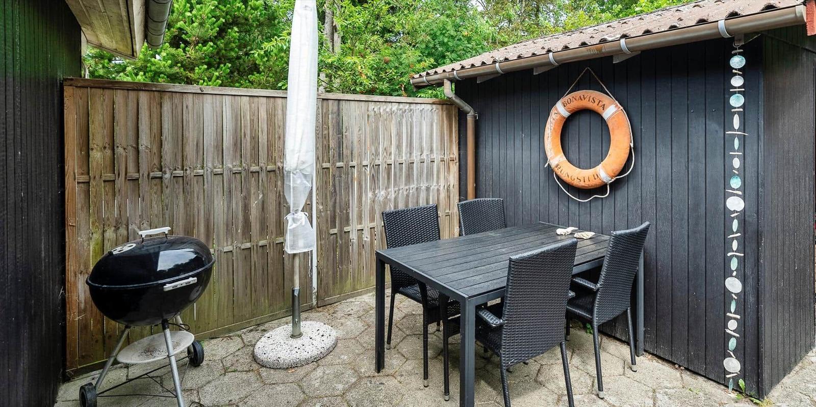 Hinterhof mit Grill, Tisch und Stühlen. An der Wand hängt ein Rettungsring.