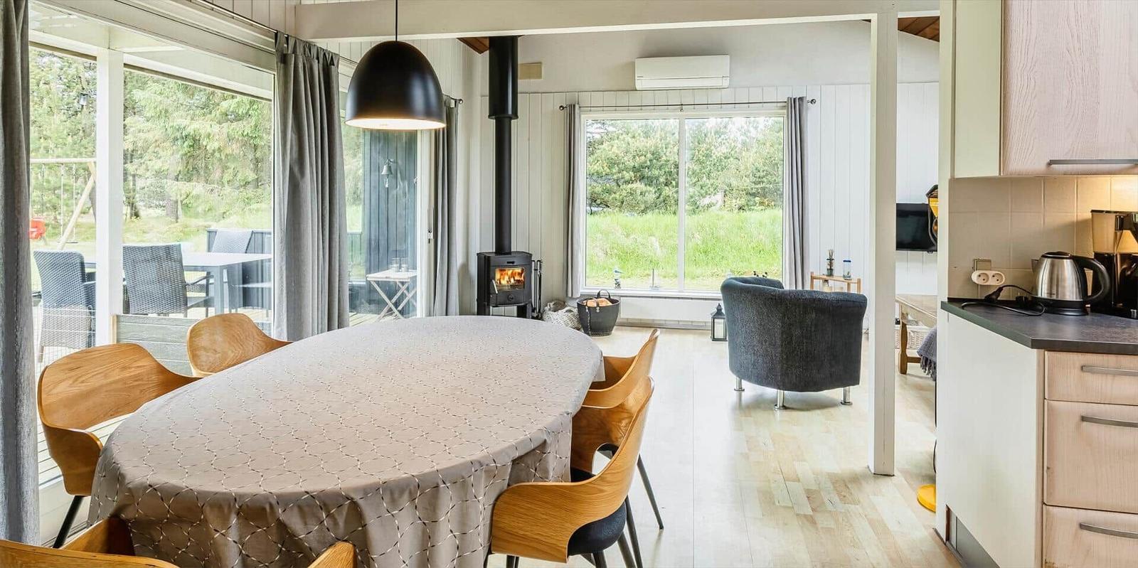 Essbereich mit Tisch und Stühlen, Kamin und Blick auf die Terrasse.
