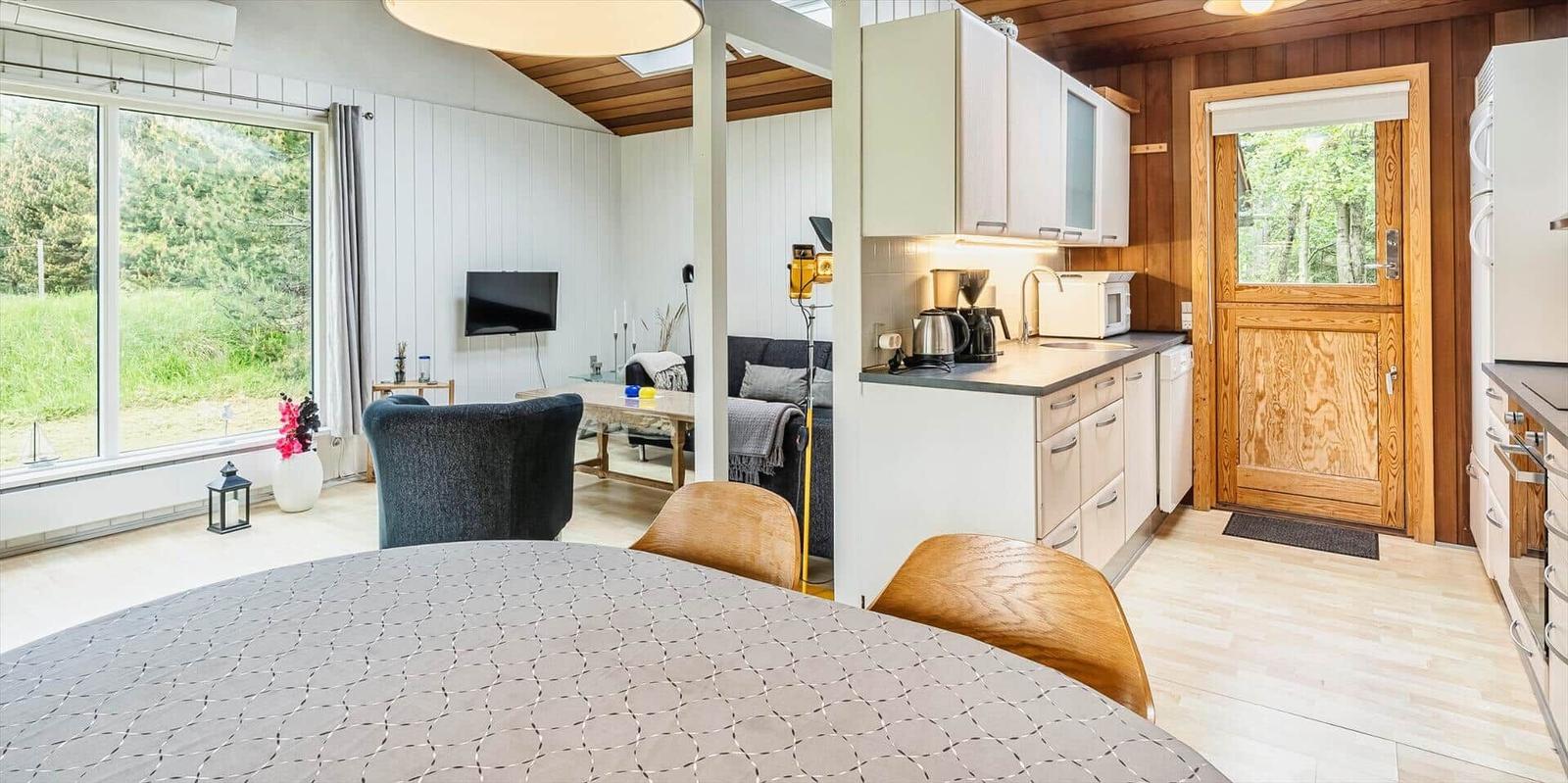 Küche mit Essbereich, Wohnzimmer und Blick auf Grünflächen.