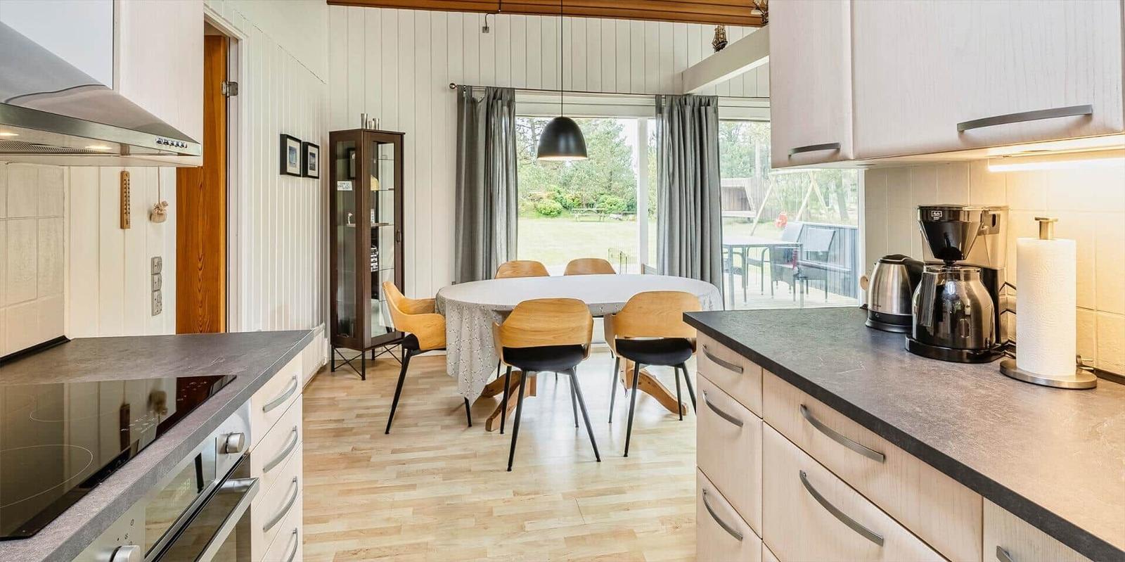 Küche mit Esstisch und Sicht auf Garten. Holzfußboden und moderne Geräte.