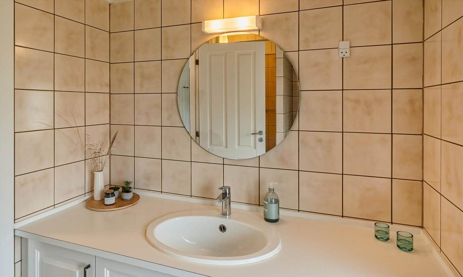 Bad mit Waschbecken, Spiegel und Fliesenwand