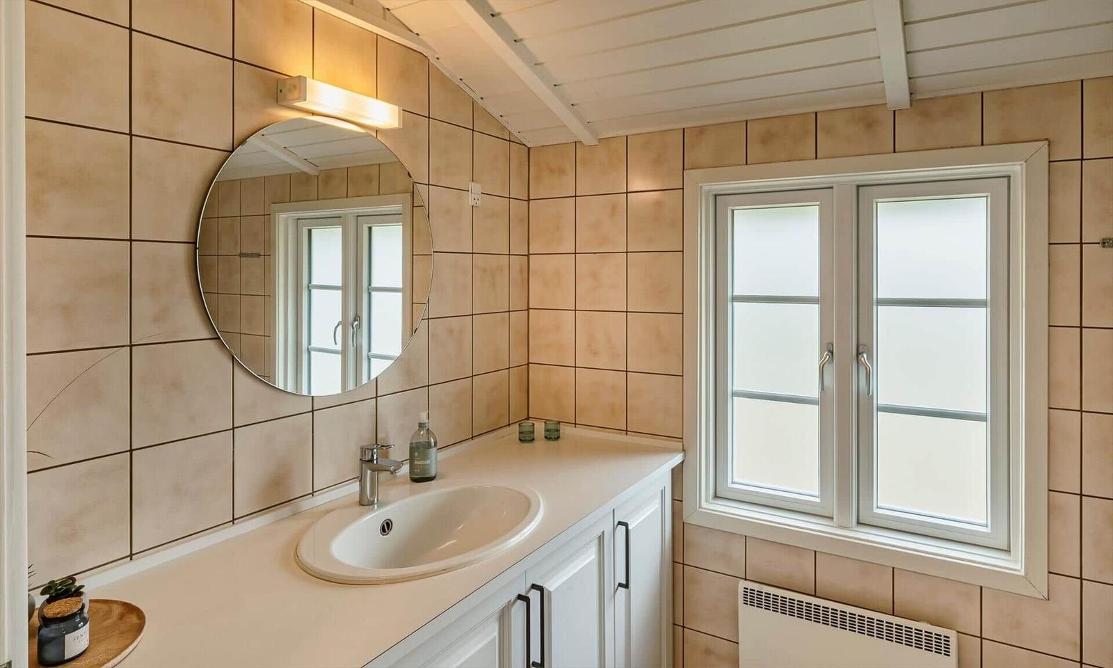 Badezimmer mit Waschbecken, Spiegel und Fenster