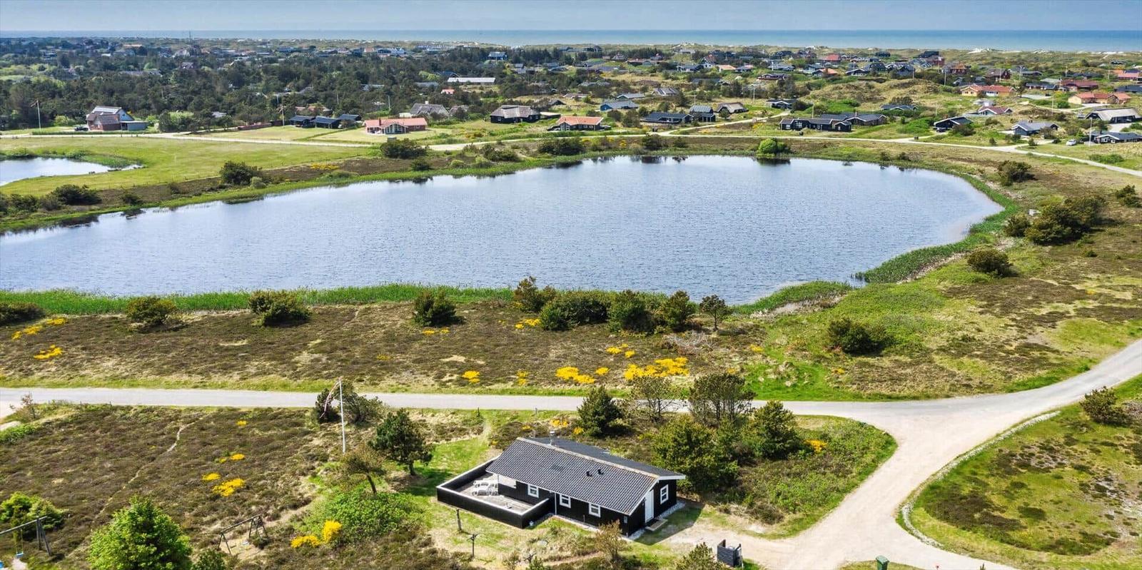 Ein Haus am See mit Blick auf die Küste und grüne Landschaft.