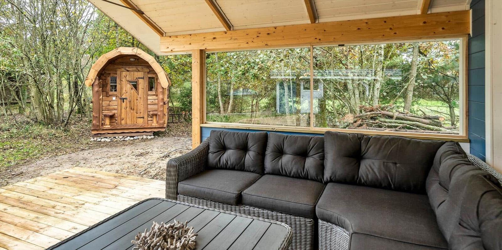 Terrasse mit Sitzgruppe und Blick auf Wald und Holzhaus