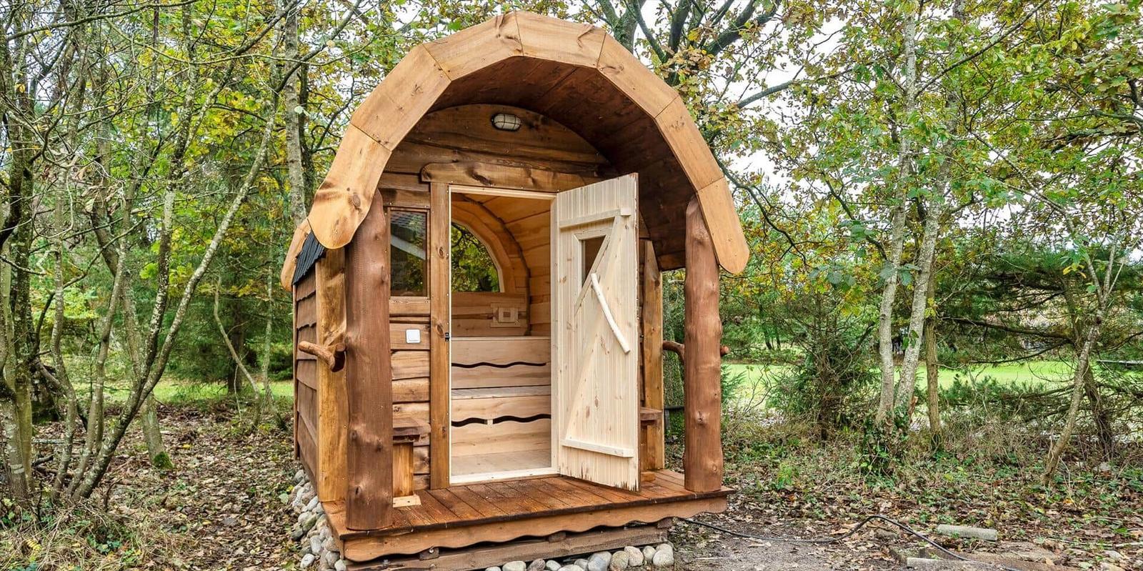 Holzsauna im Wald mit offener Tür und Sitzbänken