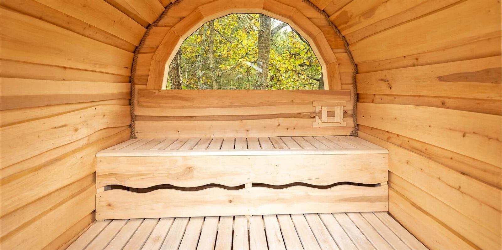 Holzsauna mit Sitzbank und Bogenfenster zum Wald
