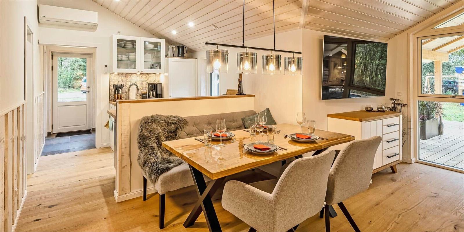 Essbereich mit Holztisch, Stühlen und Küchenbereich im Hintergrund.