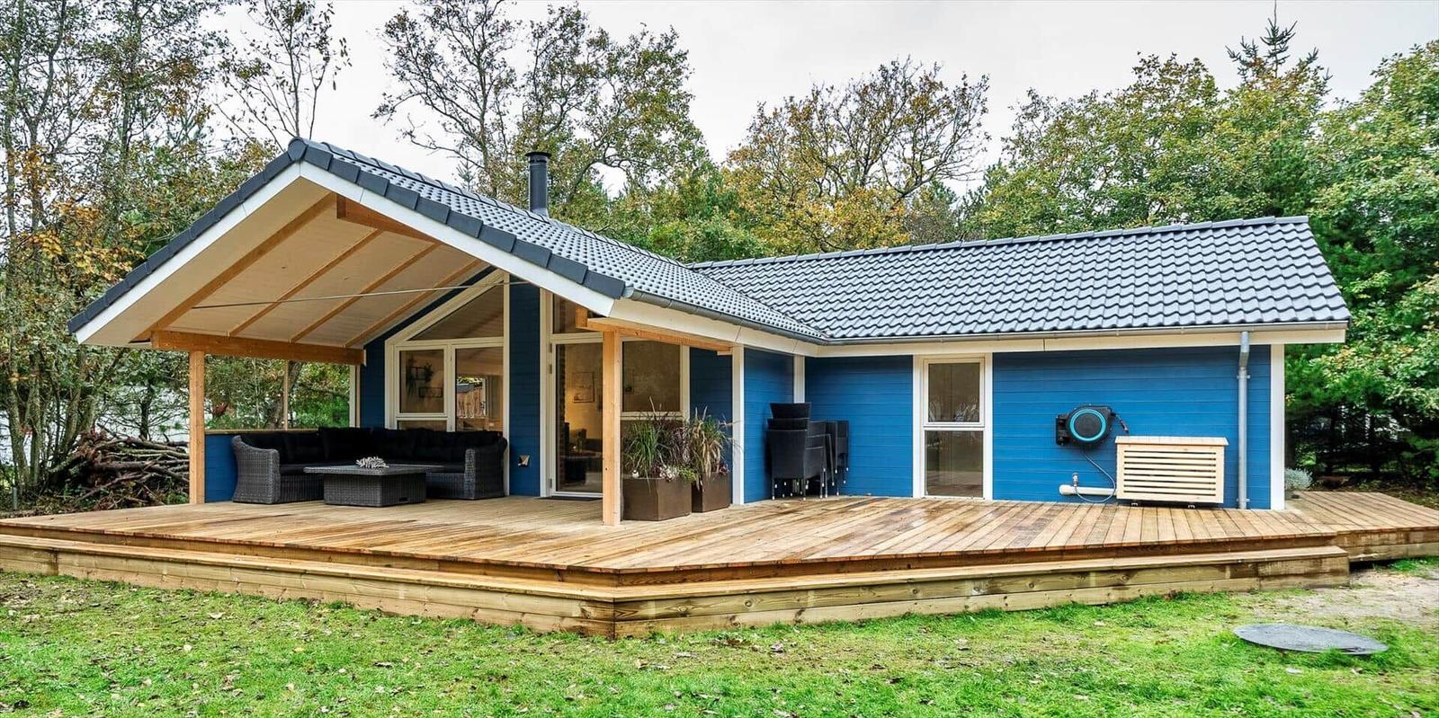 Blauer Holzhaus mit Terrasse und Garten. Außendeko und Sitzgelegenheiten.
