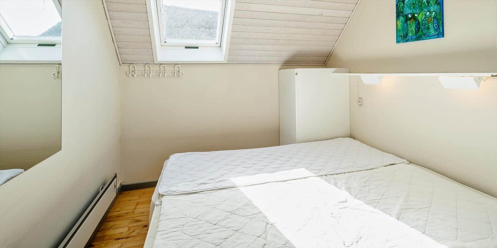 Schlafzimmer mit Dachschrägen, Dachfenster und weißem Bett.