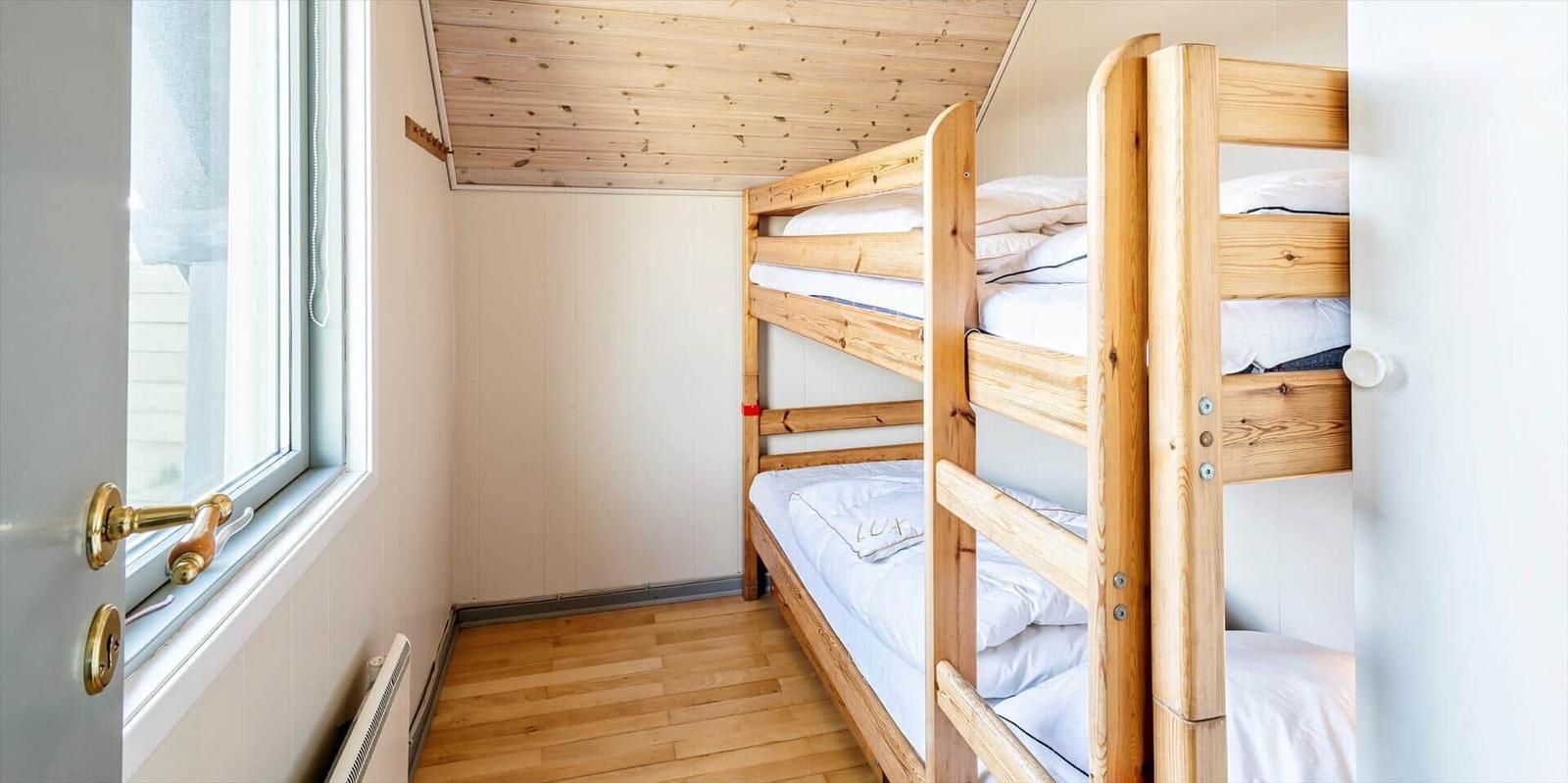 Ein Raum mit Holzbett und Fenster. Holzdecke und Boden.