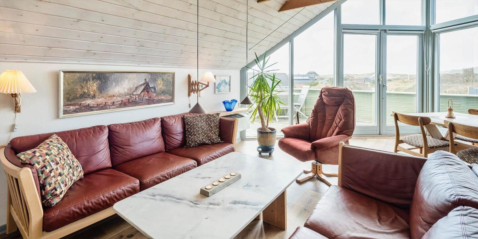 Wohnzimmer mit Ledersofa, Couchtisch und Blick auf Terrasse