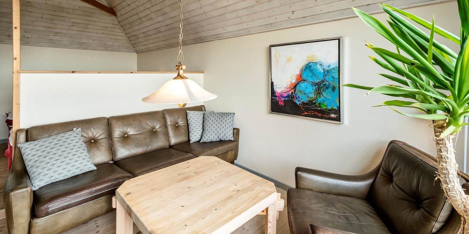 Wohnzimmer mit Ledersofa, Holztisch und Wandbild.
