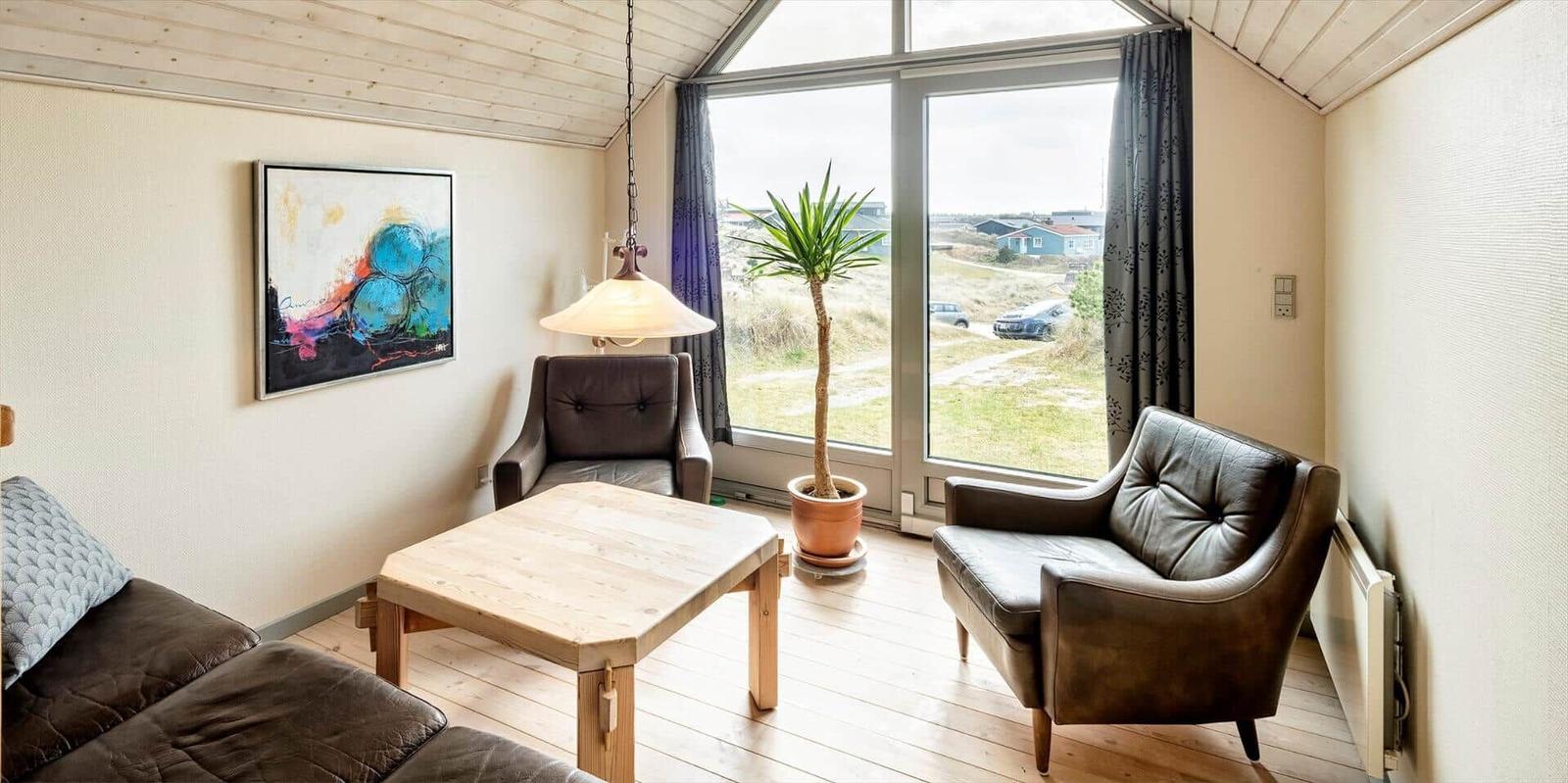 Wohnzimmer mit Sitzgelegenheiten, Tisch und Blick auf Außenbereich.