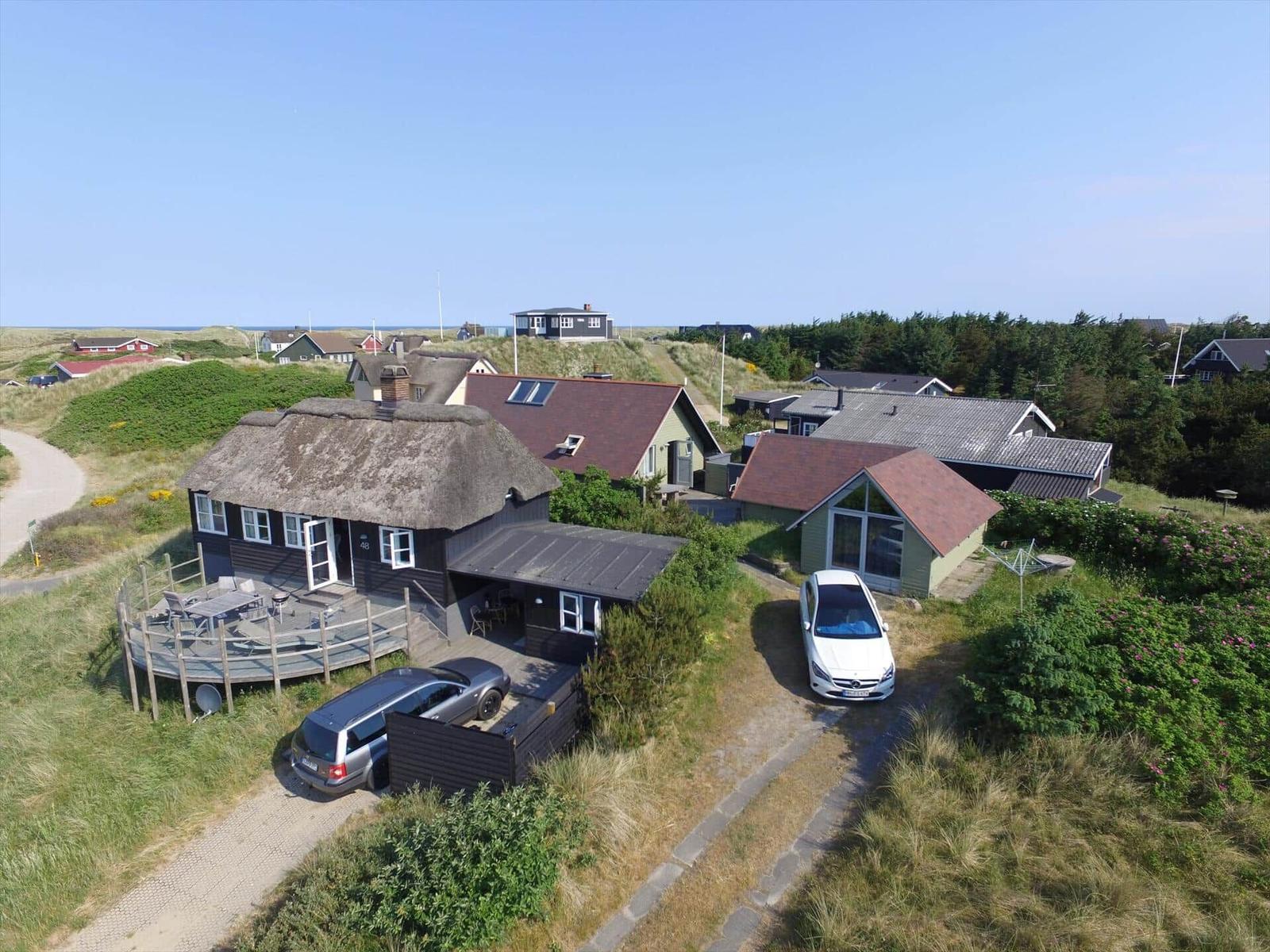 Haus mit Strohdach, Terrasse und Parkplatz auf grüner Anhöhe