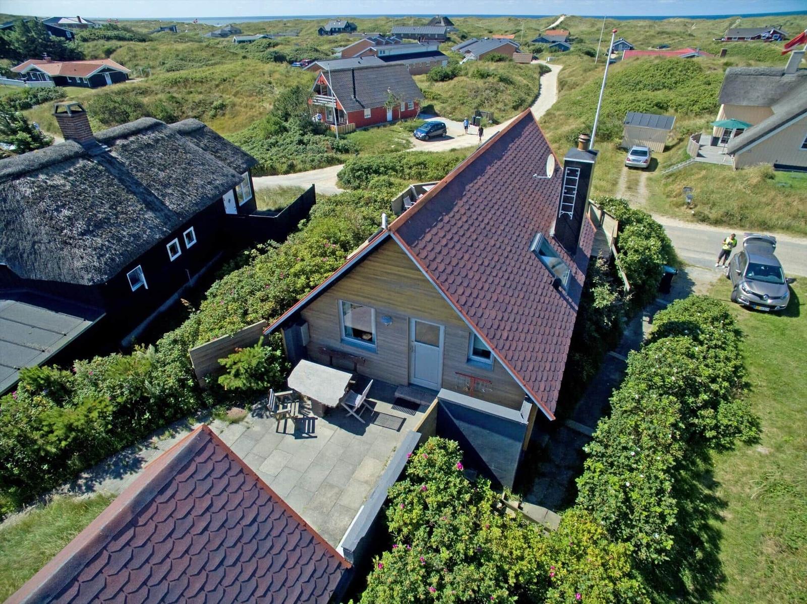 Haus mit Terrasse und Garten. Umgebung mit Grünflächen und weiteren Häusern.